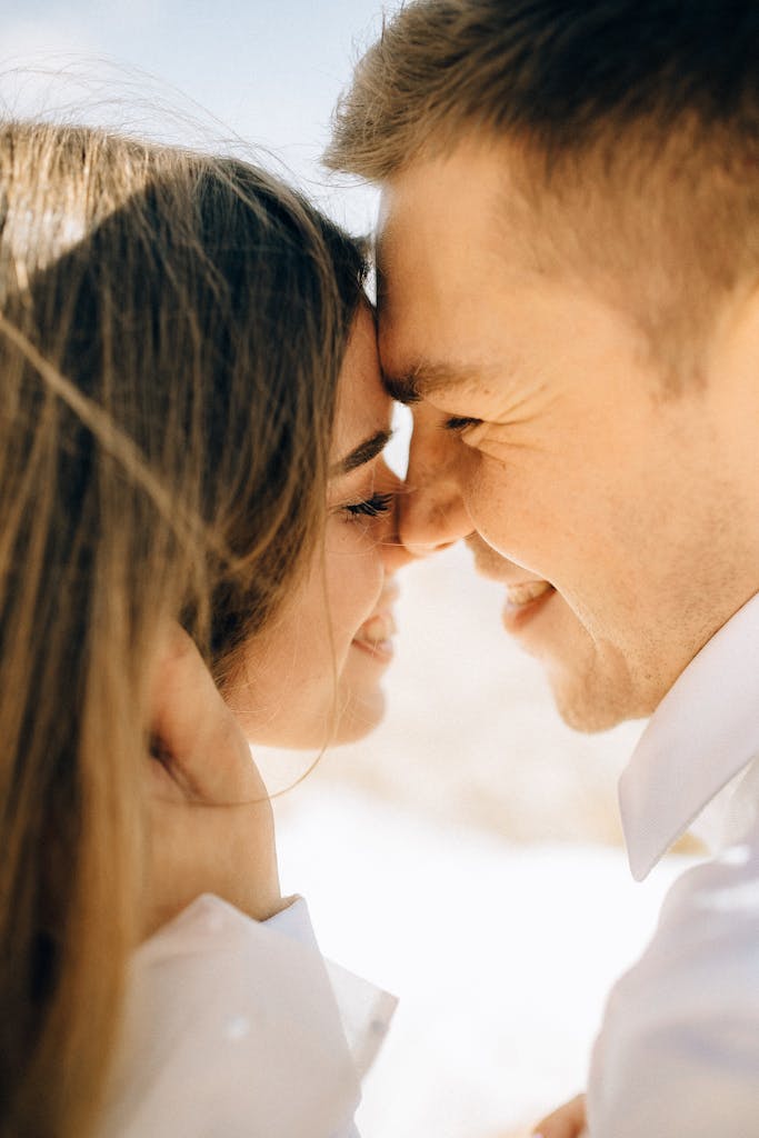 Close-up of a smiling couple sharing a romantic moment outdoors in daylight.